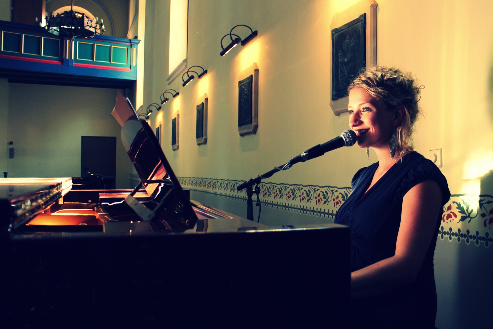 Anne Fraune singt am Flügel in einer Kirche und lächelt