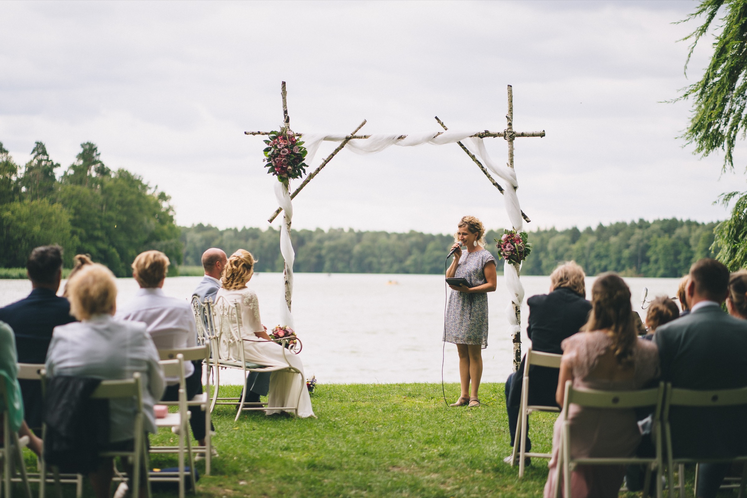 Freie Trauung im Freien am See, Gäste sitzen vor einem Blumenbogen